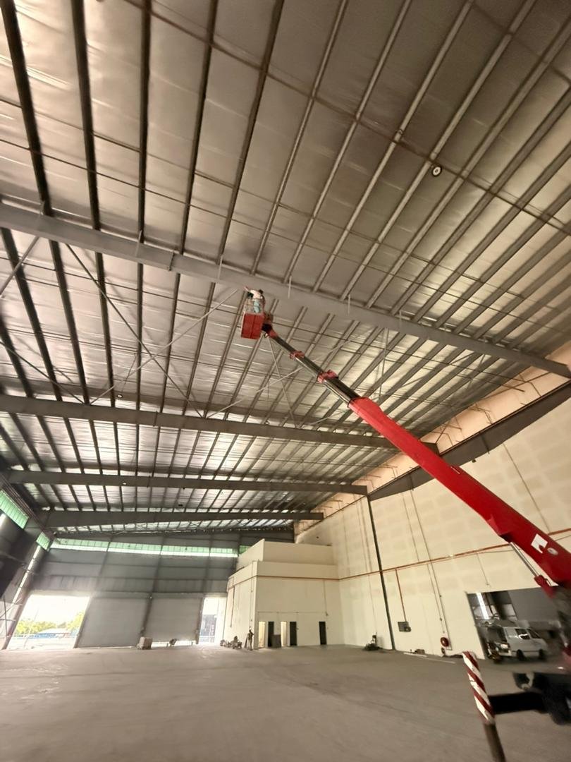 Juruteknik menggunakan boom lift untuk kerja pemasangan di siling tinggi sebuah gudang industri.